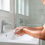 Hygiène des mains au quotidien : les bons réflexes pour limiter les contaminations Une femme se nettoyant les mains à l’évier dans une salle de bain moderne, sous une lumière naturelle douce.