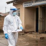 Soignant en tenue de protection devant un centre de surveillance épidémiologique en Afrique centrale.