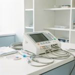 Poste d’électrocardiographie moderne et accessoires soigneusement rangés dans un cabinet médical lumineux.